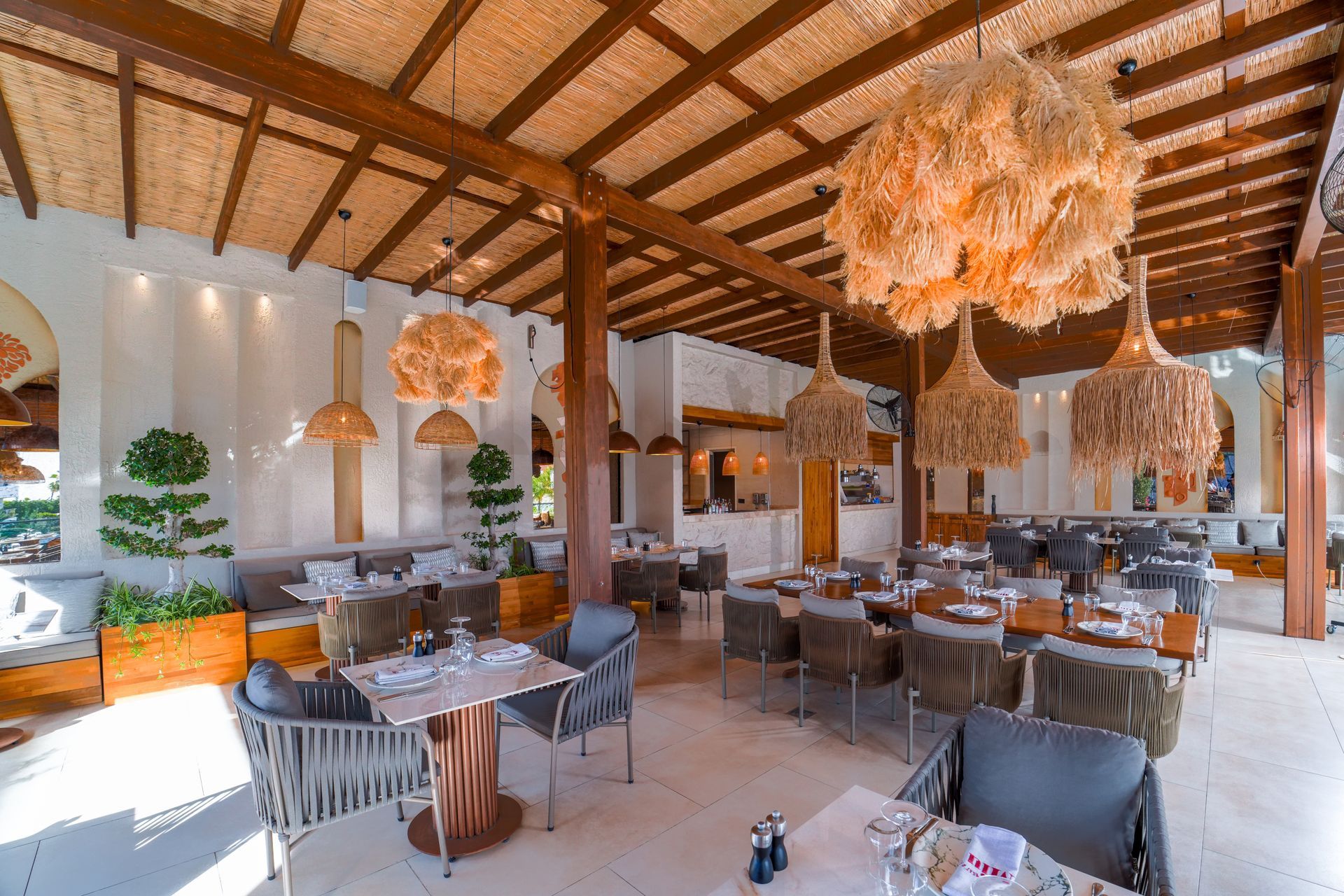 Liu Resorts | Restaurant interior with tables, chairs, decorative hanging lights, and a wooden ceiling.