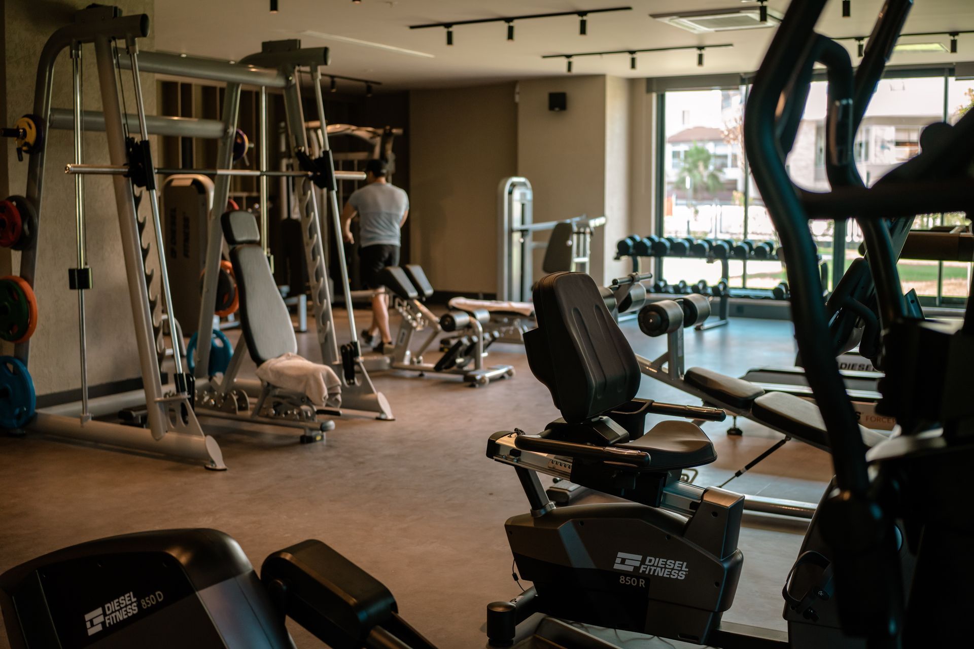 Liu Resorts | Gym interior with weight machines, a person on a treadmill, and free weights.
