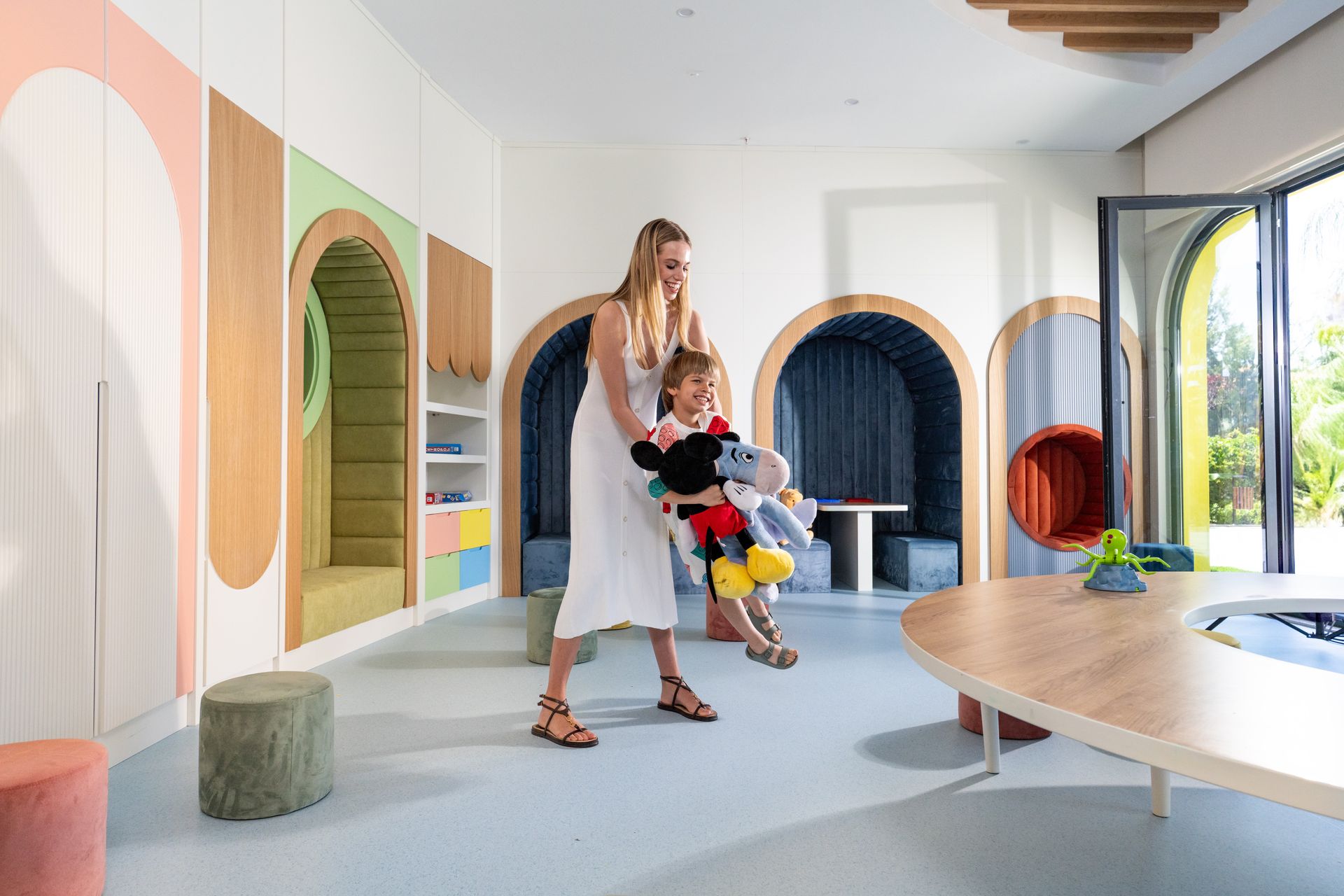 Liu Resorts | Woman holding child in a colorful playroom.