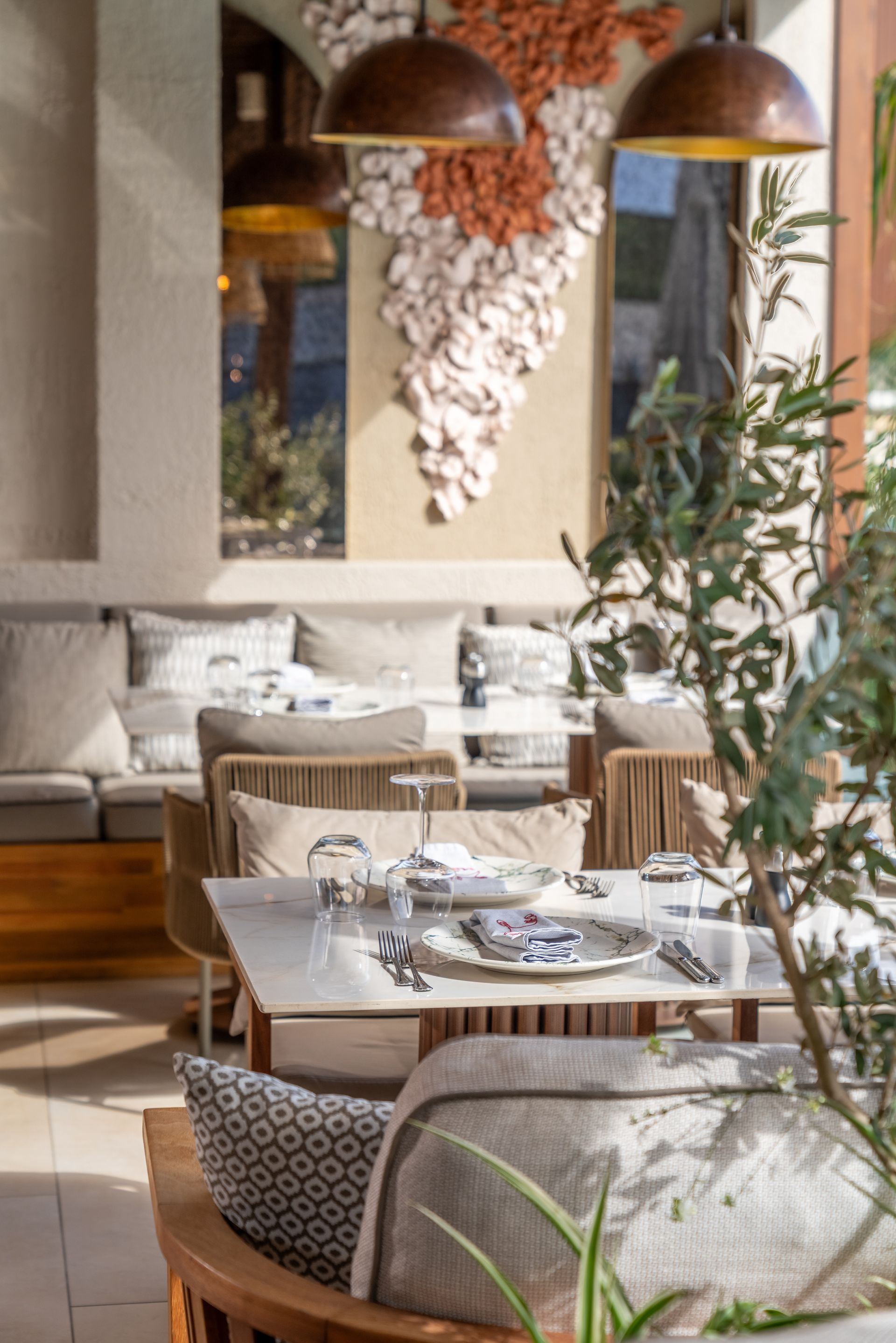 Restaurant interior with tables set for dining, neutral tones, and decorative shell art.
