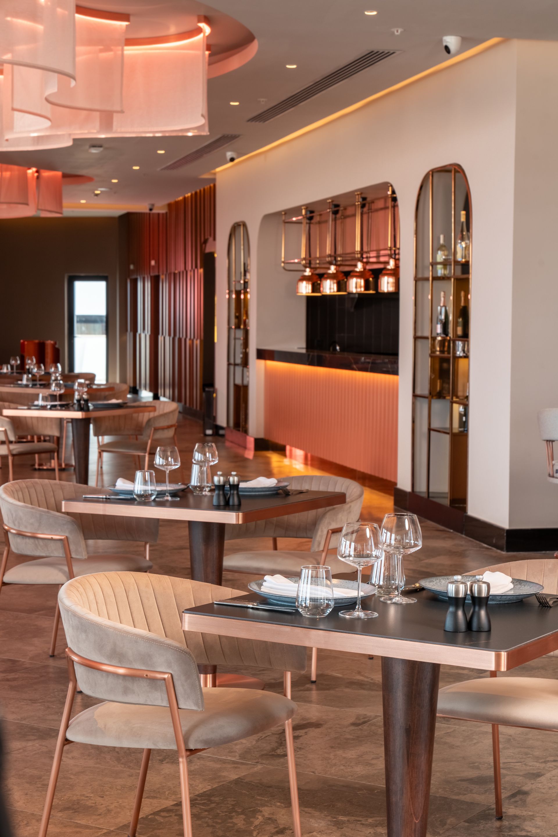 Liu Resorts | Interior view of a modern restaurant with tables set for dining and a bar in the background. 