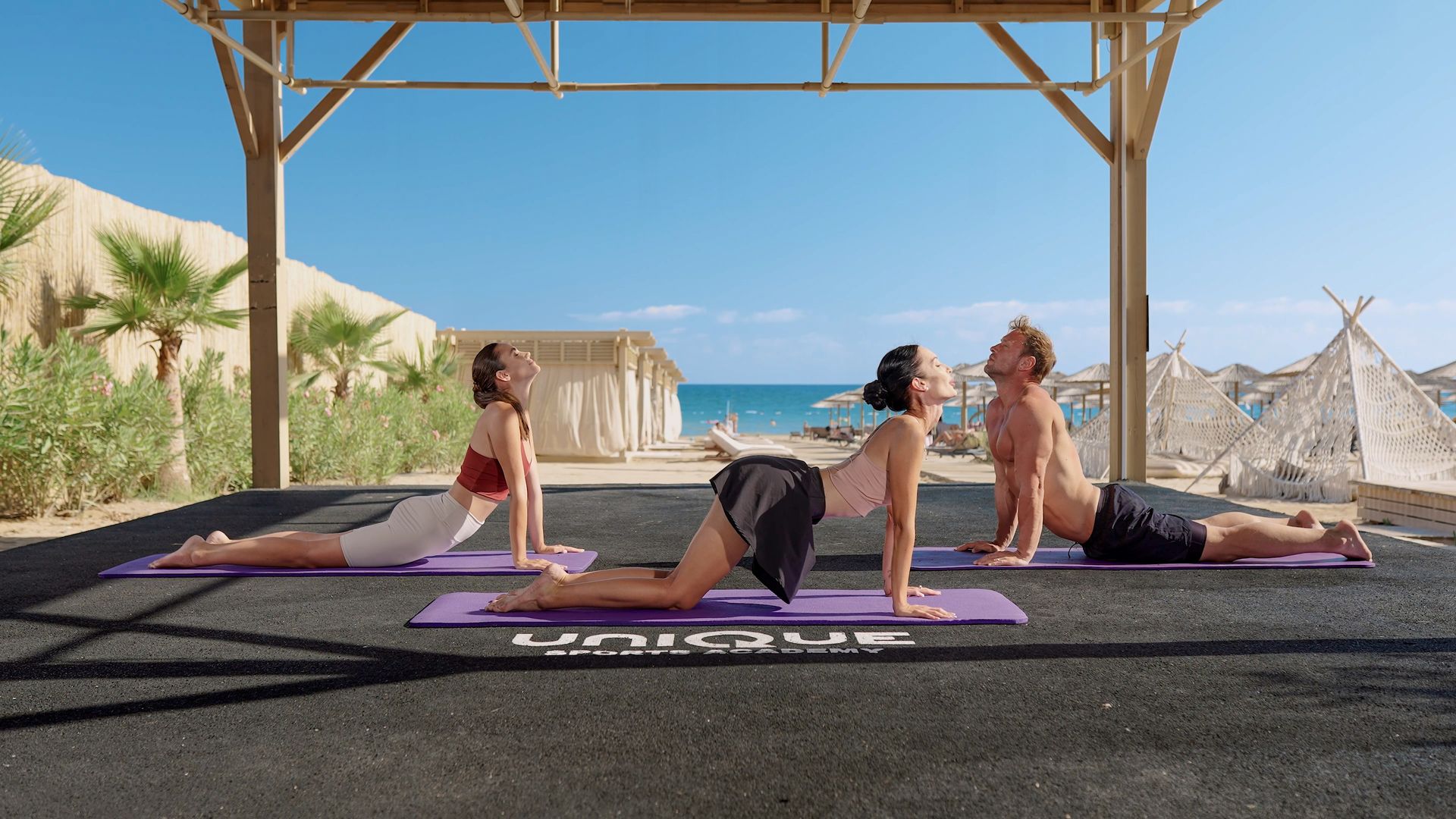 Liu Resorts | Three people doing yoga on mats near the beach.