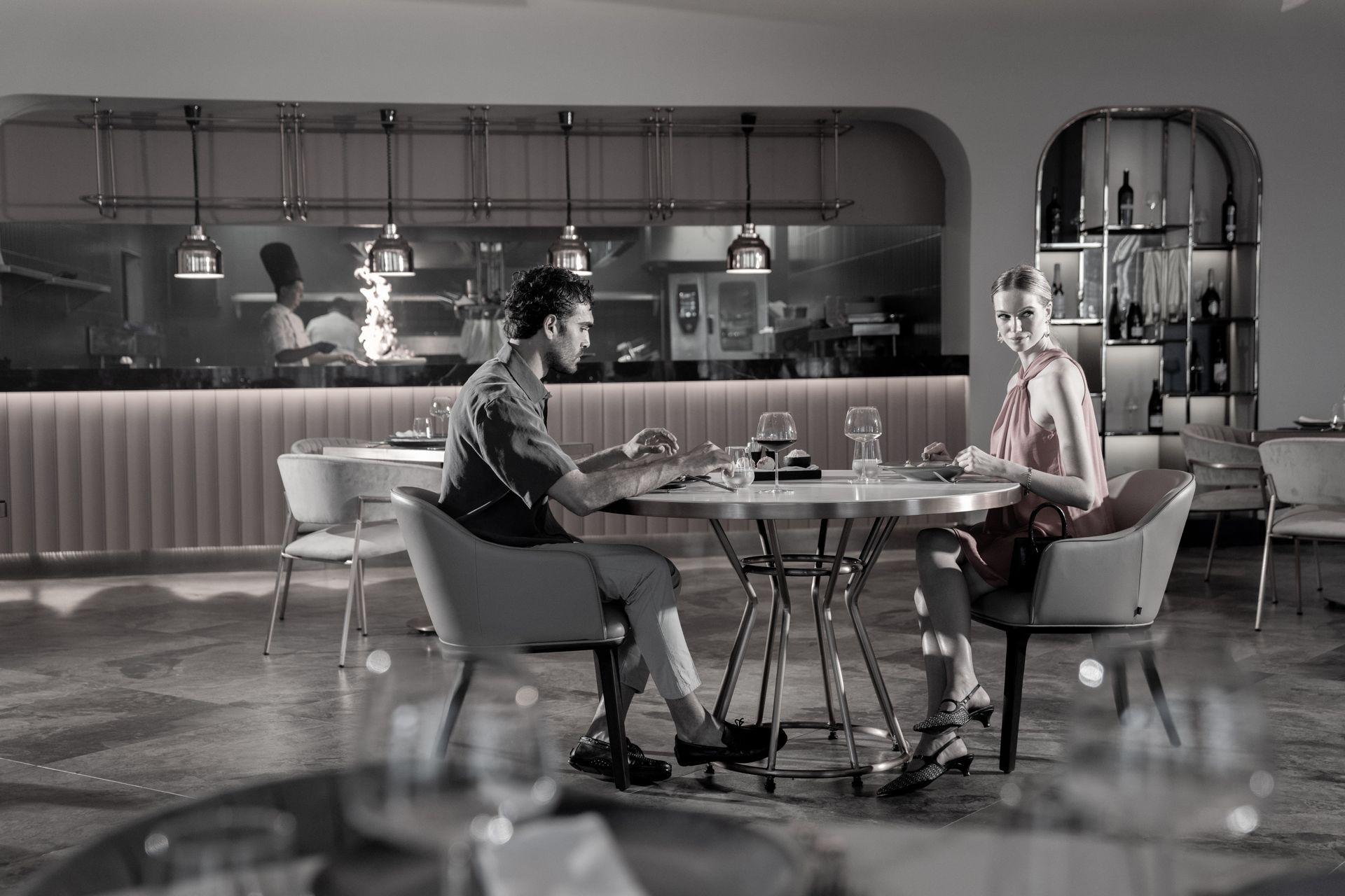 Liu Resorts | A couple dining in a restaurant, a kitchen is visible in the background.