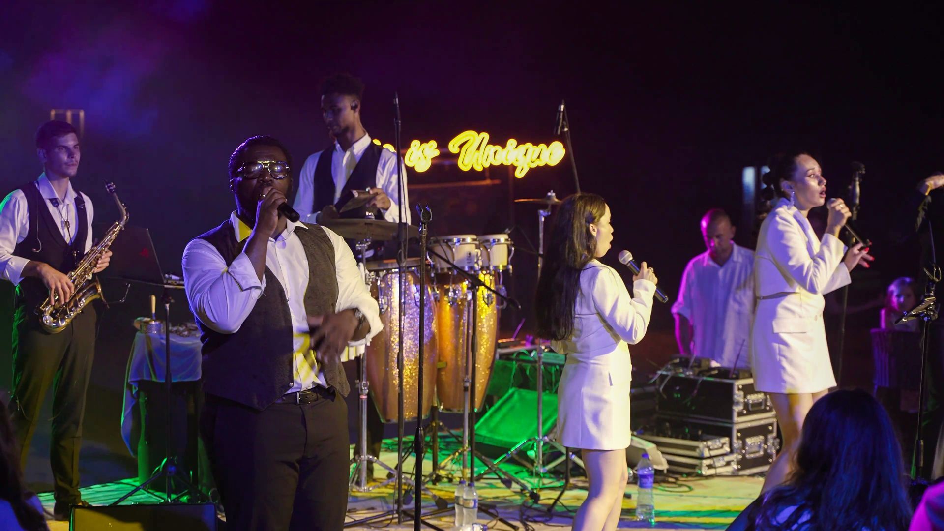 Liu Resorts | Band performing on stage at night with neon sign.