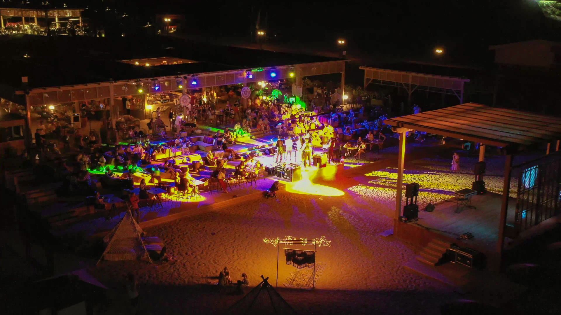Liu Resorts | Nighttime outdoor event with illuminated stage, crowd, and buildings, vibrant lighting.